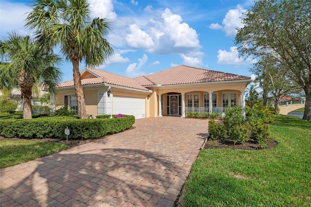 mediterranean / spanish-style house with decorative driveway, a tile roof, stucco siding, a garage, and a front lawn