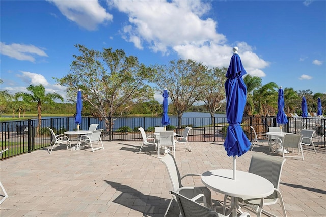 view of patio with a water view and fence