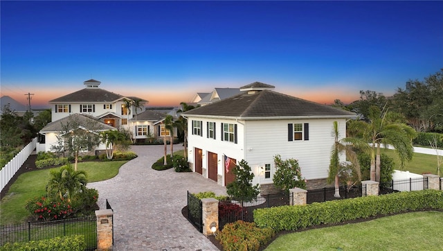 view of front of home with a garage, fence private yard, decorative driveway, and a yard