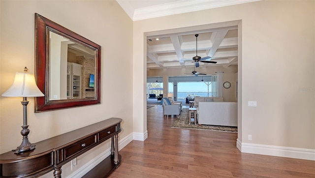 corridor featuring coffered ceiling, wood finished floors, baseboards, ornamental molding, and beam ceiling