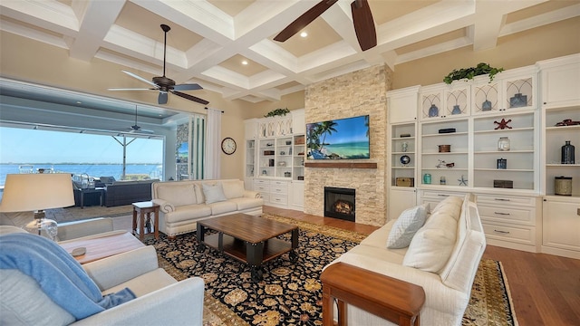 living room with beamed ceiling, coffered ceiling, dark wood-style flooring, and a stone fireplace