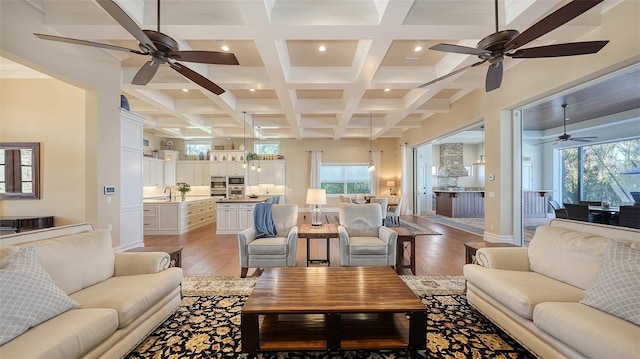 living room with light wood-style floors, baseboards, coffered ceiling, and beamed ceiling