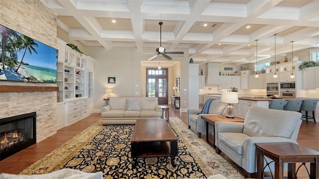 living room with beam ceiling, a fireplace, a high ceiling, and wood finished floors