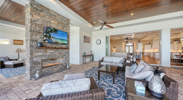 living room featuring a stone fireplace, brick floor, a raised ceiling, and wood ceiling