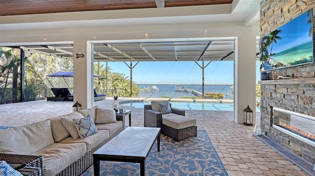 view of patio / terrace featuring an outdoor living space with a fireplace, a water view, and an outdoor pool