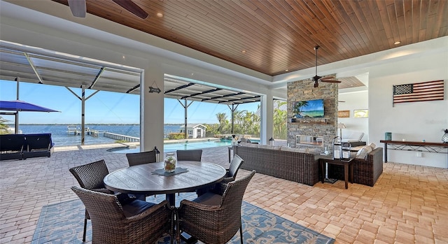 view of patio / terrace with an outdoor pool, ceiling fan, a water view, an outdoor living space with a fireplace, and outdoor dining space