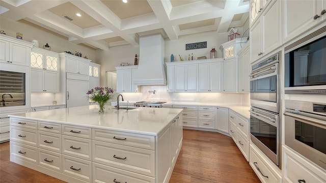 kitchen with a sink, white cabinets, decorative backsplash, dark wood-style floors, and custom range hood