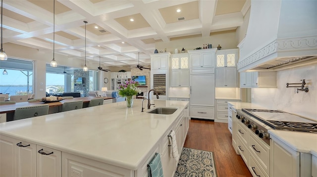 kitchen featuring premium range hood, a sink, open floor plan, dark wood-style floors, and stainless steel gas stovetop