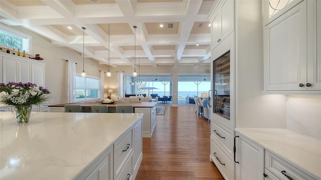 kitchen with dark wood-type flooring, white cabinetry, beamed ceiling, and hanging light fixtures