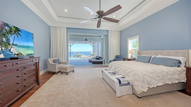 bedroom with access to outside, a tray ceiling, wood finished floors, and crown molding