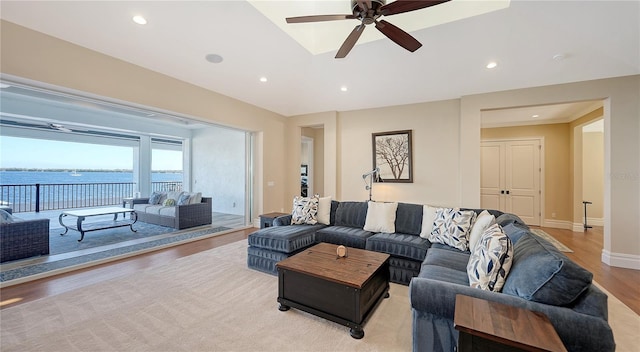 living area with light wood finished floors, recessed lighting, a water view, a ceiling fan, and baseboards