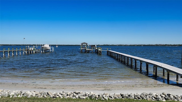 view of dock with a beach view, a water view, and boat lift