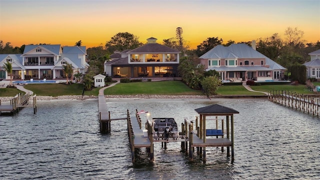 dock area with a water view, boat lift, and a yard