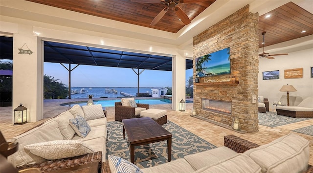 view of patio with glass enclosure, an outdoor living space with a fireplace, a ceiling fan, and an outdoor pool