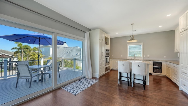 kitchen with a kitchen island, beverage cooler, white cabinets, and dark wood finished floors