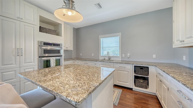 kitchen with double oven, visible vents, a sink, and white cabinetry