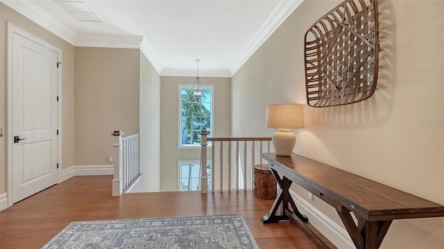 hallway with crown molding, an upstairs landing, wood finished floors, a chandelier, and baseboards