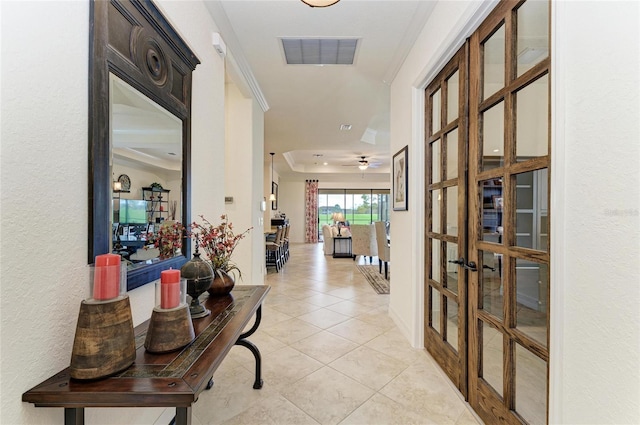 hall with light tile patterned floors, french doors, ornamental molding, and visible vents