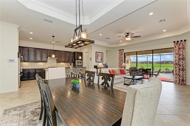 dining space with a raised ceiling, visible vents, and crown molding