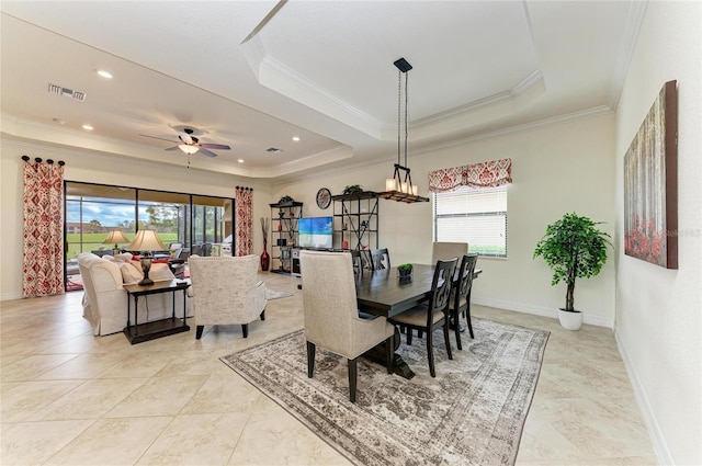 dining area featuring baseboards, a tray ceiling, visible vents, and crown molding