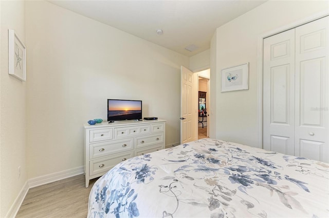 bedroom with a closet, light wood-style flooring, and baseboards