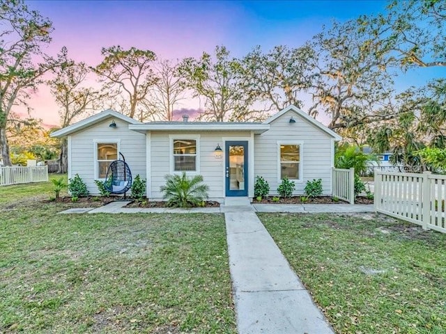 view of front of home featuring a lawn and fence