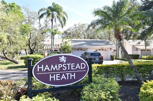 community / neighborhood sign featuring an attached garage and driveway