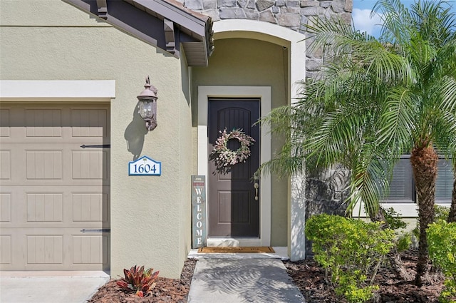 doorway to property featuring an attached garage and stucco siding