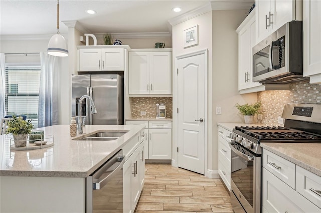 kitchen featuring white cabinets, appliances with stainless steel finishes, pendant lighting, and a sink