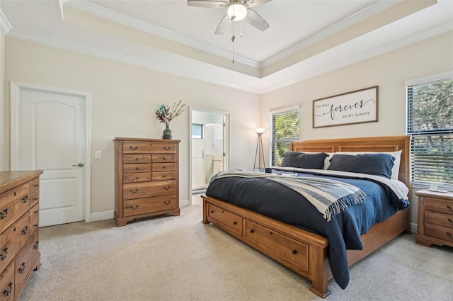 bedroom featuring a tray ceiling, ensuite bathroom, crown molding, and light colored carpet