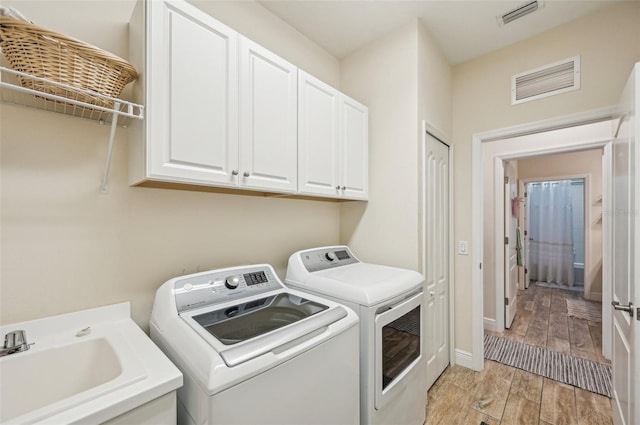 laundry area with cabinet space, washing machine and dryer, visible vents, and wood tiled floor