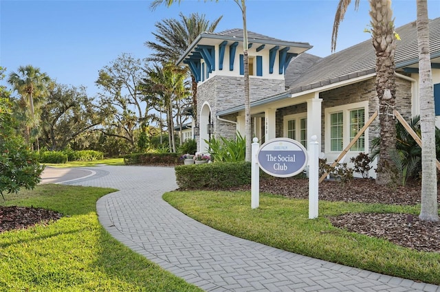 exterior space featuring stone siding, stucco siding, and a front yard