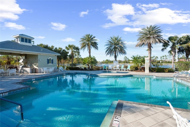 community pool with a patio area and fence