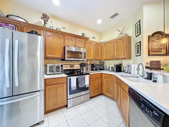 kitchen featuring a sink, visible vents, light countertops, appliances with stainless steel finishes, and brown cabinetry