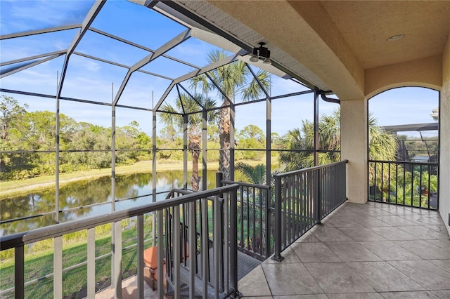 view of patio / terrace with glass enclosure, a water view, and a balcony