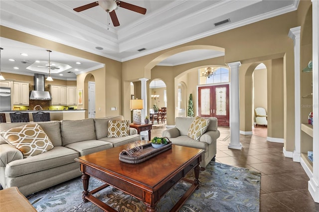 living area with arched walkways, dark tile patterned flooring, a tray ceiling, decorative columns, and crown molding