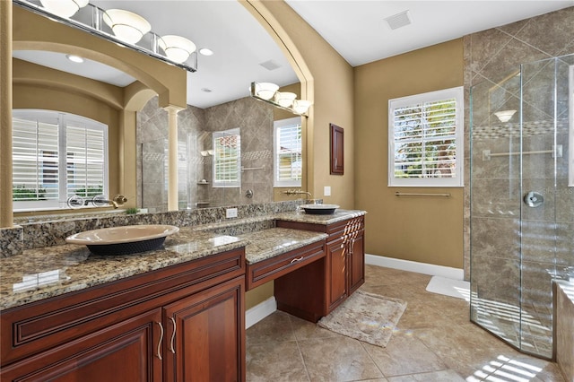 bathroom featuring a sink, visible vents, baseboards, tiled shower, and double vanity