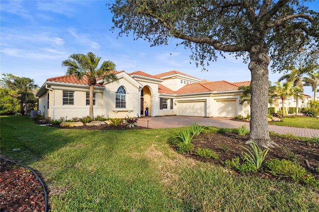 mediterranean / spanish-style home with a garage, driveway, a tiled roof, a front lawn, and stucco siding