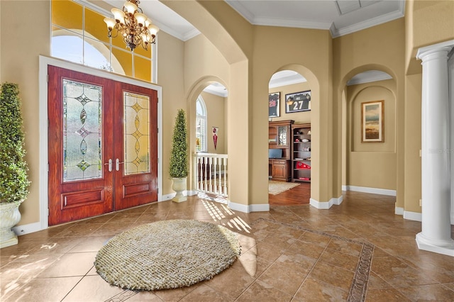 foyer with a high ceiling, baseboards, ornate columns, an inviting chandelier, and crown molding