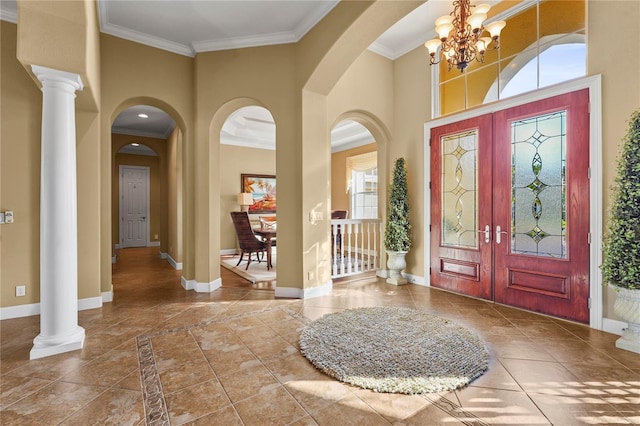 foyer featuring ornate columns, a high ceiling, baseboards, and ornamental molding