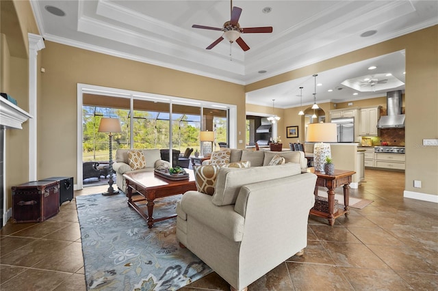 living room featuring ornamental molding, dark tile patterned flooring, a raised ceiling, and a ceiling fan