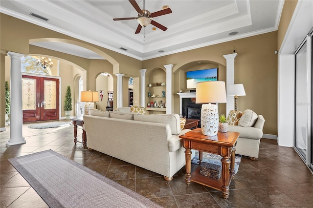 living room with built in features, a raised ceiling, and decorative columns