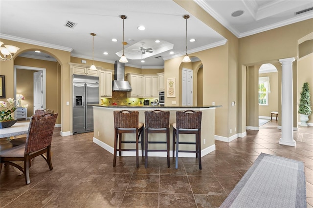 kitchen with visible vents, arched walkways, cream cabinets, stainless steel appliances, and wall chimney range hood