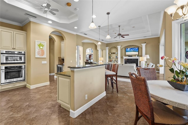 kitchen featuring a fireplace, a tray ceiling, open floor plan, and cream cabinetry