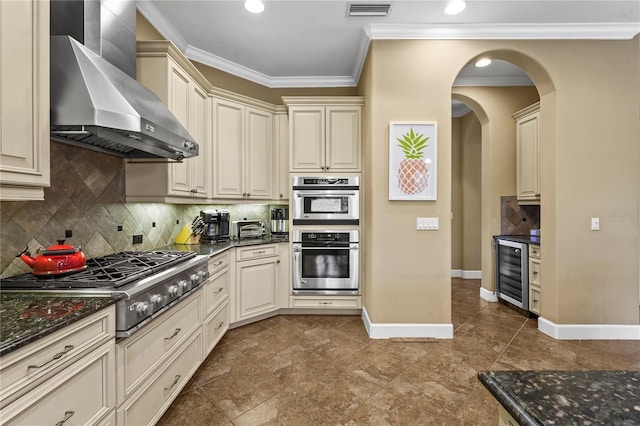 kitchen featuring wall chimney exhaust hood, wine cooler, cream cabinets, and stainless steel appliances