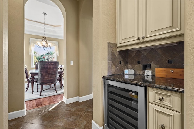 bar with wine cooler, arched walkways, a notable chandelier, tasteful backsplash, and baseboards