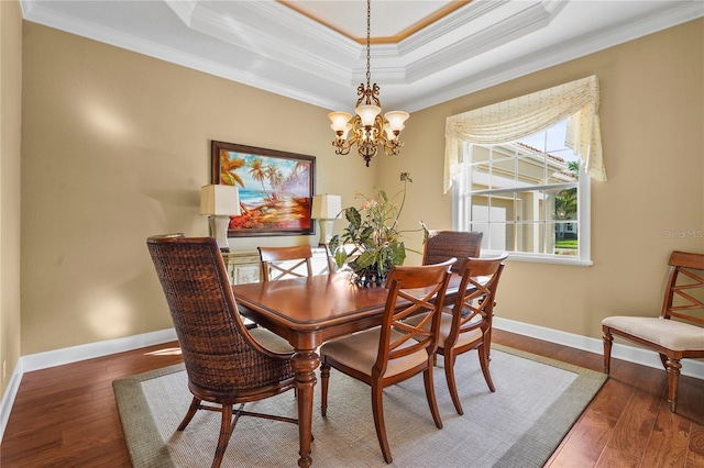 dining room with a tray ceiling, wood-type flooring, and baseboards