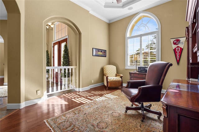 sitting room with baseboards, wood-type flooring, arched walkways, and crown molding