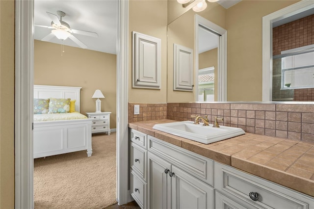 ensuite bathroom with ensuite bathroom, tasteful backsplash, ceiling fan, and vanity