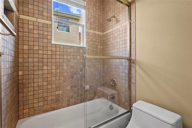 bathroom featuring toilet, bath / shower combo with glass door, and a textured wall